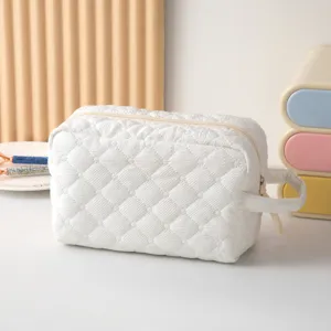 Primer plano detallado de un neceser blanco acolchado con diseño de rombos.