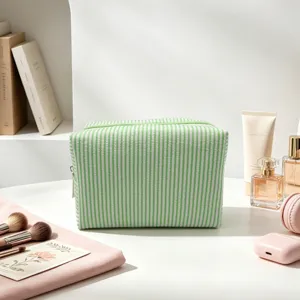 Détail d'une trousse à maquillage en seersucker rayé vert et blanc avec fermeture
