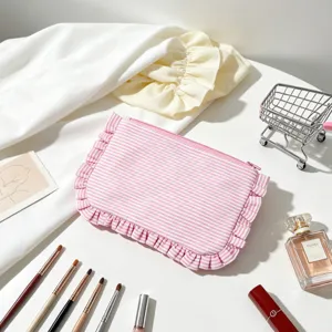 Detail of pink striped seersucker makeup pouch with ruffles in a vanity setting