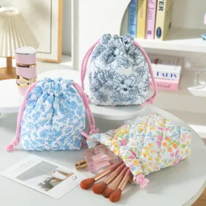 Close-up of quilted floral drawstring storage bags with makeup brushes and perfume