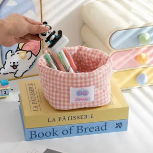 Vue détaillée du panier de rangement en tissu vichy rose avec papeterie sur livres