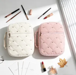 Detalle de neceseres acolchados en crema y rosa con estampado de lazos decorativos