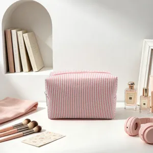 Trousse de maquillage rayée en seersucker sur une coiffeuse avec des accessoires.