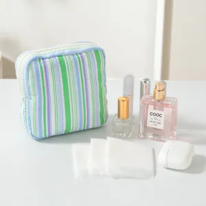 Close-up detail view of the striped seersucker pouch with perfume and beauty essentials