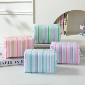 Group of striped seersucker makeup bags in fresh pastel colors and soft textures.