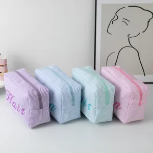 Gros plan sur quatre trousses de toilette à rayures colorées avec broderies fines