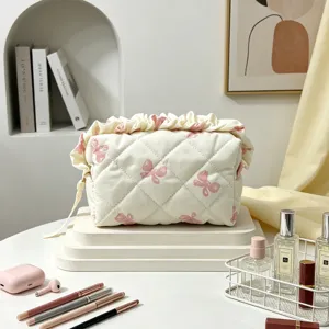 Detail des rosa Schleifenmusters und des Rüschenbesatzes an dieser gesteppten Kosmetiktasche