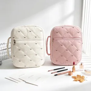 Primer plano de bolsas acolchadas blancas y rosas con varios cosméticos en mesa
