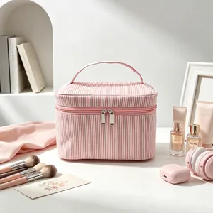 Vue détaillée d'une trousse à maquillage en seersucker rose rayé dans un décor de style.