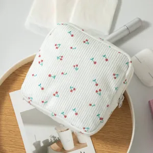 Dettaglio in primo piano della borsetta portaoggetti in velluto a coste bianco con fiori.