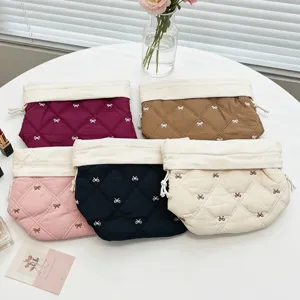 Quilted drawstring cosmetic bags with embroidered bows in various colors shown in detail