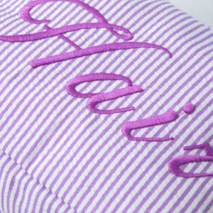 Vue macro détaillée de la broderie Stacie violette sur le tissu rayé d'une trousse
