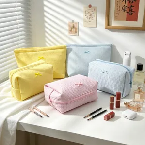 Primer plano de bolsas de maquillaje gofradas con un lazo en colores pastel