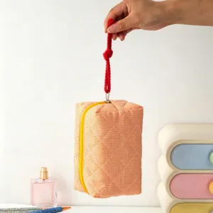 Neceser acolchado de cuadros con cuerda roja en un entorno de estilo de vida limpio.
