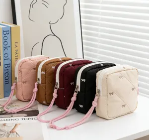 Detailed view of quilted cosmetic bags with bow embroidery in five soft colors