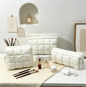 Elegante juego de tres neceseres blancos acolchados con accesorios de maquillaje de lujo