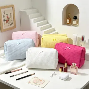 Detalle de neceseres de maquillaje coloridos de tejido gofre con lazos decorativos