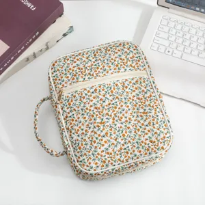 Gesteppte Buchschutzhülle mit Blumenmuster, Griff und Reißverschluss auf weißem Tisch