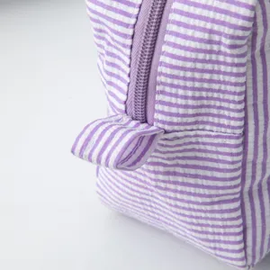Gros plan détaillé montrant la texture seersucker rayée violet et blanc d'une trousse