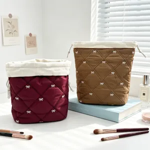 Detailed view of quilted cotton drawstring makeup bags with white bow embroidery