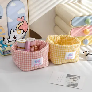 Gros plan de jolis paniers de rangement en tissu vichy rose et jaune sur un bureau ensoleillé
