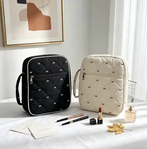 Detalle de bolsas acolchadas con lazos, lápiz labial y perfume en mesa blanca