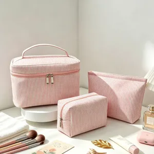 Détail de trousses de maquillage en seersucker à rayures roses avec accessoires de voyage.