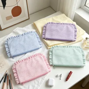 Detail view of four pastel seersucker striped makeup bags with ruffled edges and zippers