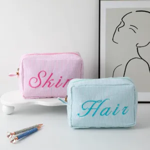 Vue détaillée de trousses de maquillage à rayures roses et bleues avec broderie