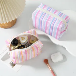 Detail view of striped seersucker makeup bags showing storage capacity and texture