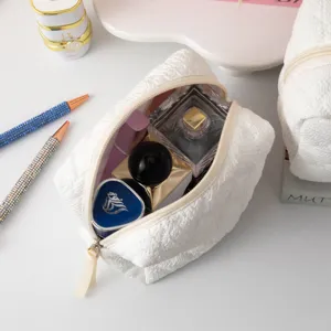 Vista detallada del neceser de maquillaje blanco texturizado con perfumes y cosméticos