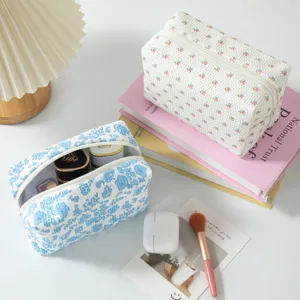 Duo von Blumen-Kord-Kosmetiktaschen mit Lifestyle-Accessoires wie Büchern und Pinseln