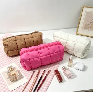 Neceser acolchado en rosa, marrón y blanco con diversos accesorios de maquillaje