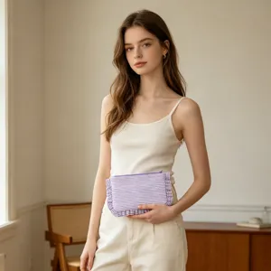 Lifestyle view of a woman holding a purple striped seersucker cosmetic bag with ruffles