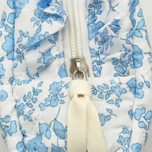 Nahaufnahme einer gesteppten floralen Kosmetiktasche mit Reißverschluss und Rüschen