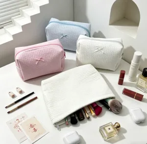 Neceser de textura gofrada con lazos y accesorios de maquillaje.