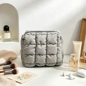 Primer plano de la bolsa de maquillaje gris acolchada con textura suave.