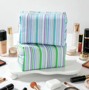 Close-up of two seersucker striped makeup bags stacked on a white elegant vanity tray