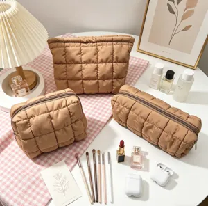 Vista detallada de tres neceseres acolchados caqui con accesorios de maquillaje