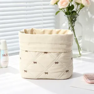 Detail of quilted cotton makeup bag with cute brown bow embroidery and soft lining