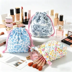 Detail of quilted floral drawstring cosmetic bags with makeup brushes and perfume.