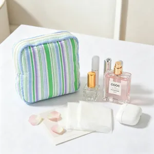 Detail of striped seersucker storage bag with cosmetics and sanitary pads on a white table