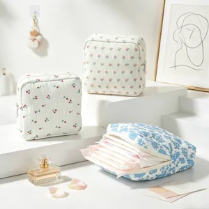 Dettaglio della borsa porta assorbenti in velluto a coste con motivo floreale e comoda chiusura a zip.
