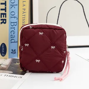 Detailed view of the elegant maroon quilted cosmetic pouch with white embroidered bows