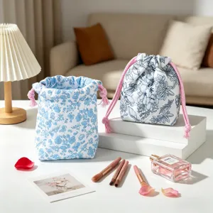 Quilted floral drawstring cosmetic pouches in blue and white on a white platform