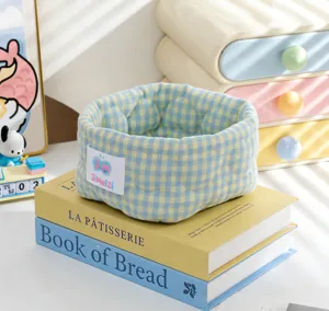 Gros plan du panier de rangement en tissu à carreaux bleu et jaune sur livres