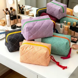 Colección de neceseres de maquillaje acolchados a cuadros en varios colores sobre un tocador