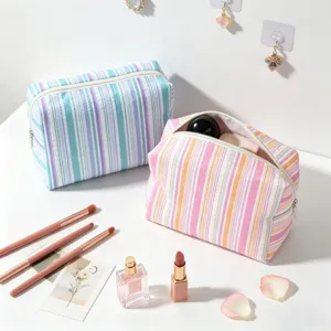 Detailed shot of fresh striped seersucker makeup bags with brushes and cosmetics