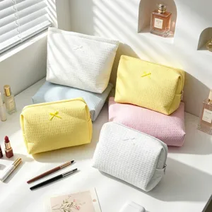 Detalle de bolsas de cosméticos con textura de gofre y lazos en varios colores pastel