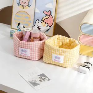 Vue rapprochée de jolis paniers de rangement en tissu à carreaux roses et jaunes pour le bureau